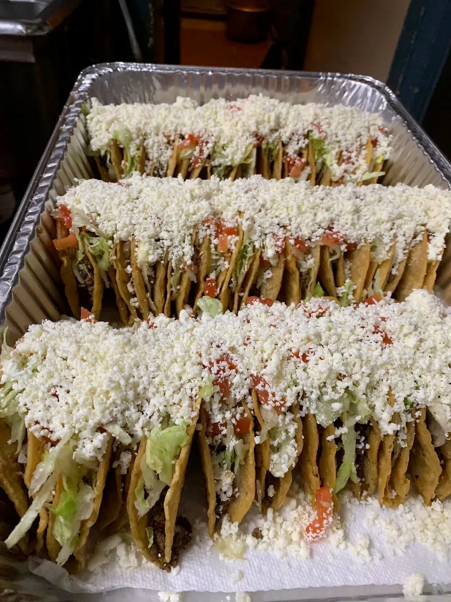 La Tapatía's real catering tray filled with tacos, lettuce, tomato and cheese